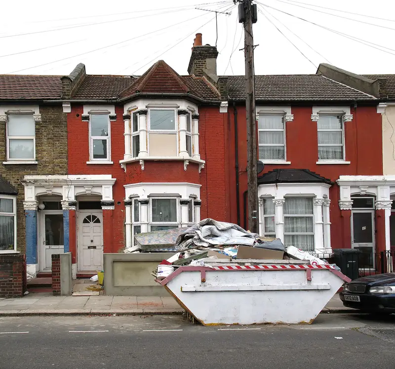 A London terrace with a skip full of household clearance outside