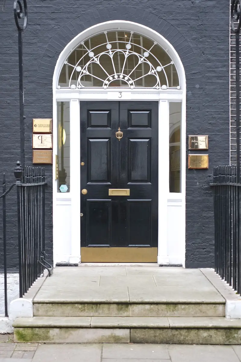 A black Georgian front door with a fanlight and stone steps